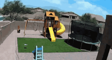 a playground with a slide and swings and a trampoline with a fence around it