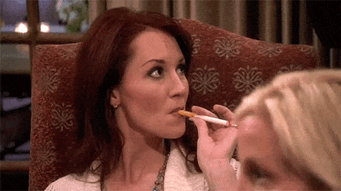two women are sitting in a chair smoking cigarettes .