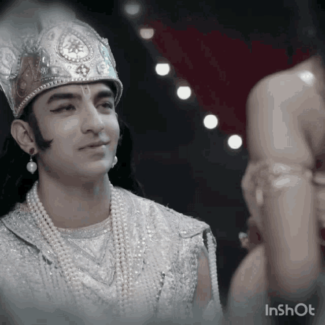 a man wearing a crown and pearls looks at another man