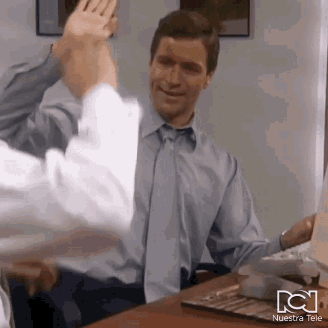 two men give each other a high five in front of a nuestra tele logo