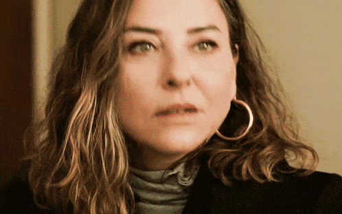 a close up of a woman wearing hoop earrings and a black jacket