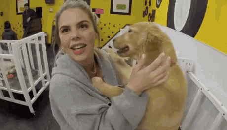 a woman is holding a puppy in her arms in a kennel .