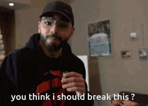a man with a beard and glasses is holding something in his hand and says " you think i should break this ? "