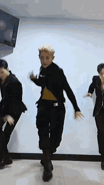 a group of men are dancing in a room with a tv in the background .