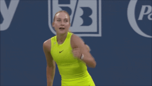 a woman in a neon yellow nike tank top celebrates a win