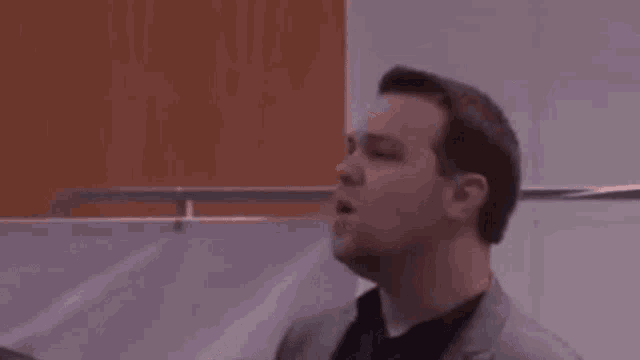 a man in a suit and tie is looking up in a room .