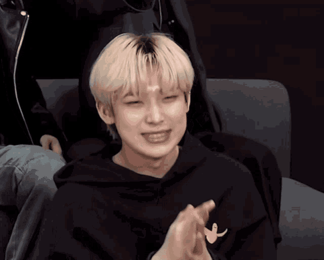 a young man with blonde hair wearing a black hoodie with a banana on it