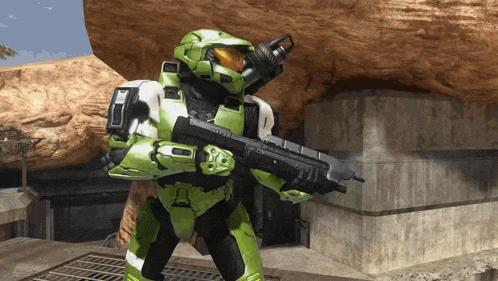 a man in a green helmet is holding a rifle in front of a rock