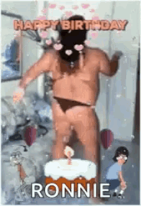 a man in a bathing suit is standing in front of a birthday cake with a candle .
