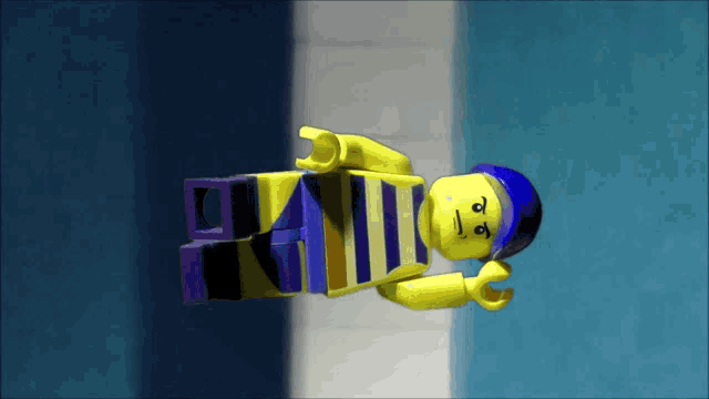 a yellow lego figure with a blue helmet and a striped shirt