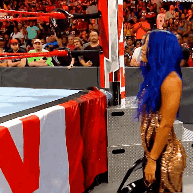 a woman with blue hair is kneeling down in front of a wrestling ring that says case on it