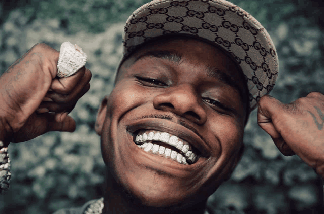a man wearing a gucci hat is smiling and holding a ring