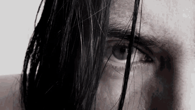 a close up of a man 's eye with long hair covering it
