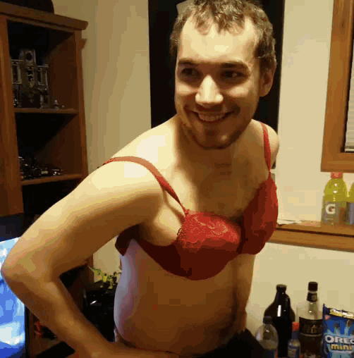 a man is wearing a red bra and smiling in front of a bottle of oreo mints