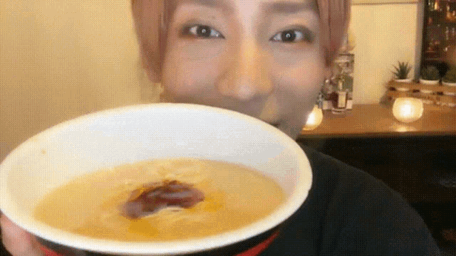 a woman with pink hair is holding a bowl of soup