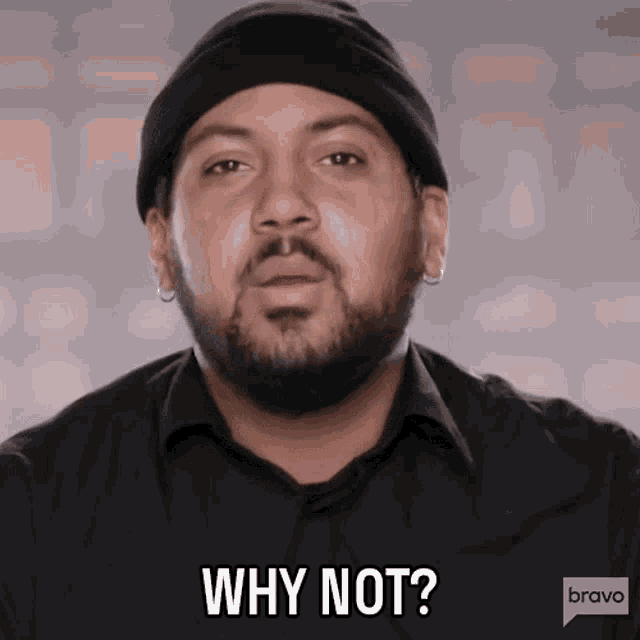 a man with a beard wearing a black shirt and a black beanie says why not