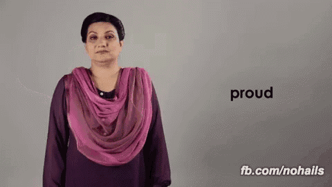 a woman wearing a pink scarf is making a sign that says proud