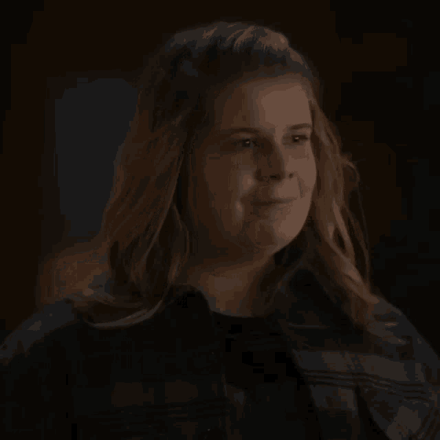 a woman in a plaid shirt is smiling and looking at the camera .