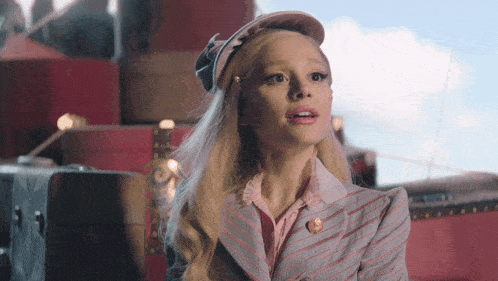 a woman wearing a hat and a striped jacket looks surprised