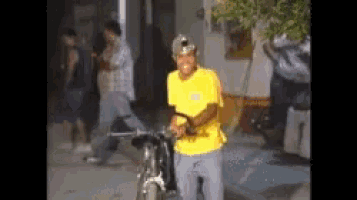 a man in a yellow shirt is standing next to a bike