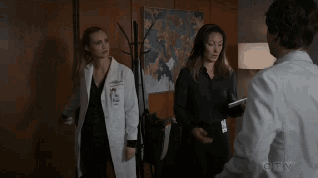 a man and two women are standing next to each other in a room with a map on the wall behind them