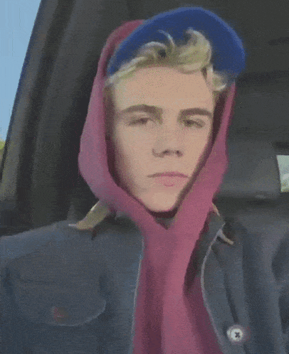 a young man wearing a blue hat and a pink scarf around his head