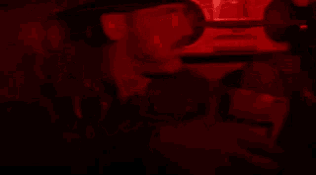 two men are singing into microphones in a dark room with red lights behind them .