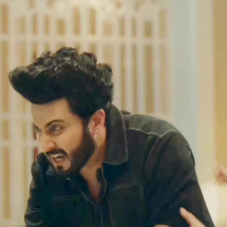 a man with a beard is talking on a cell phone while sitting at a table .