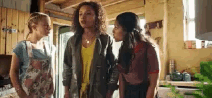 three women are standing next to each other in a kitchen and talking .