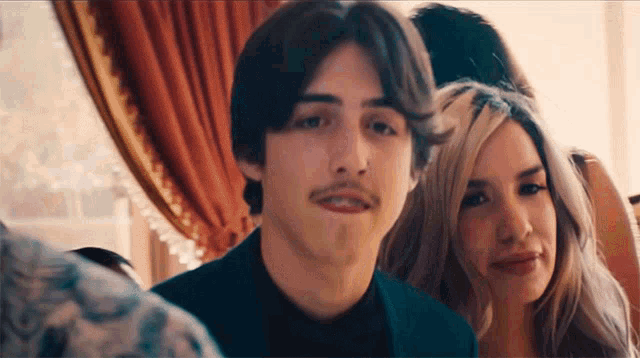 a man with a mustache and a woman with blonde hair are posing for a picture