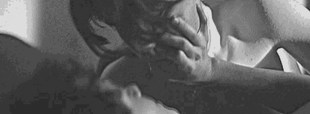 a black and white photo of a man holding a woman 's face .
