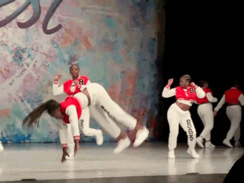 a group of dancers are performing on a stage and one of them has the number 8 on her shirt