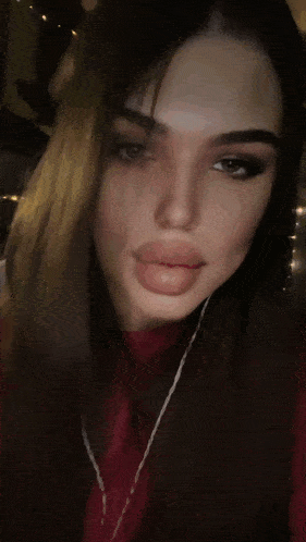 a woman in a red shirt is blowing smoke into the camera