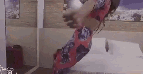 a woman is jumping on a bed in a bedroom .