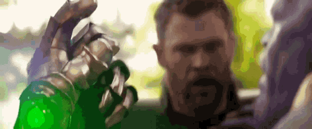 a man with a beard is holding a green glove in front of a man with a beard .