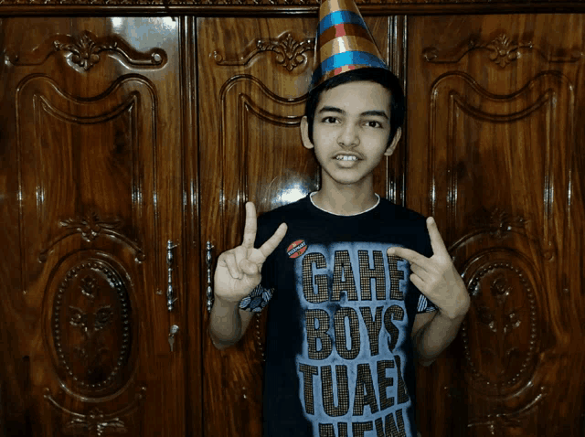 a young boy wearing a party hat and a shirt that says game boys tuaf