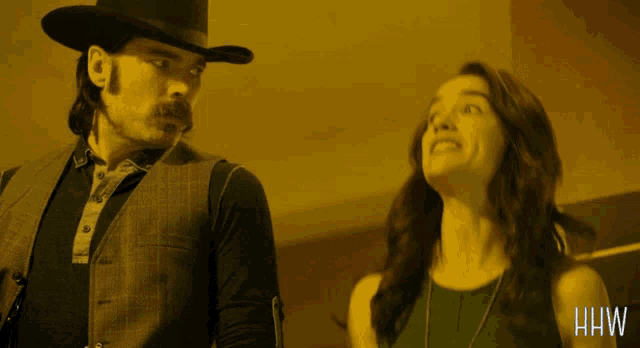 a man in a cowboy hat stands next to a woman in a green dress with the letters hw on the bottom