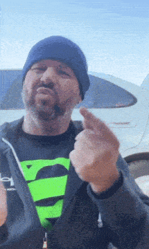 a man with a beard wearing a superman shirt and a black jacket