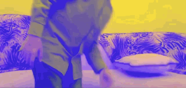 a person standing in front of a couch with a purple and yellow background