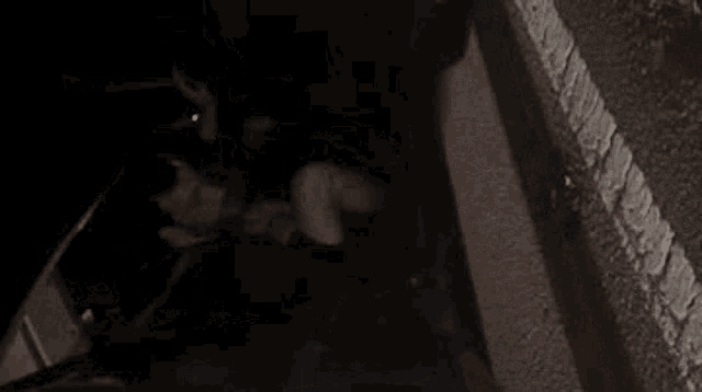 a man is laying on the ground in a dark room with a knife in his hand .