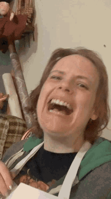 a woman wearing an apron is laughing with her mouth wide open