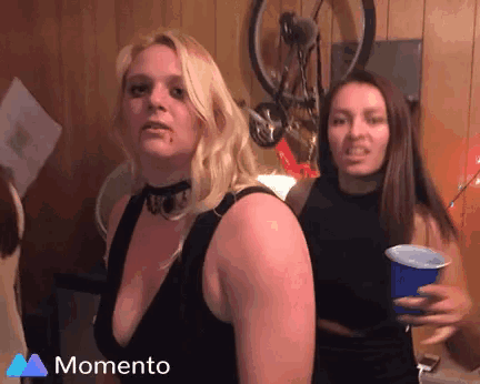 two women standing next to each other with a blue cup in front of them that says momento on the bottom