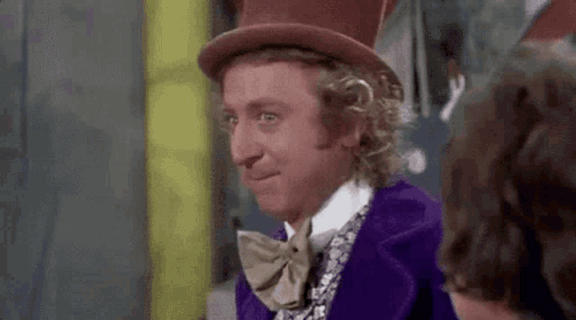 a man in a top hat and bow tie is smiling while standing next to another man .