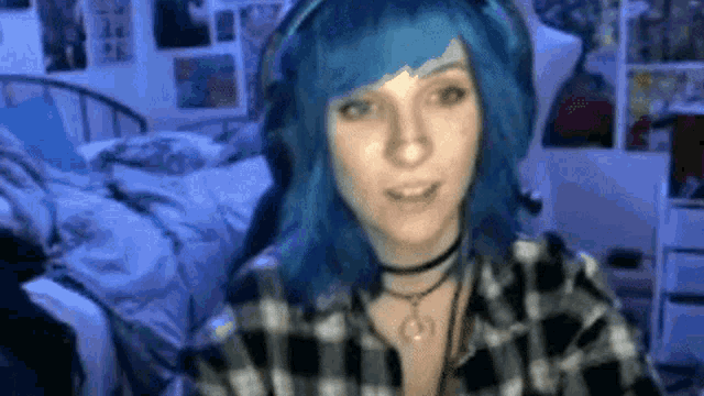 a woman with blue hair is wearing headphones and a choker necklace .