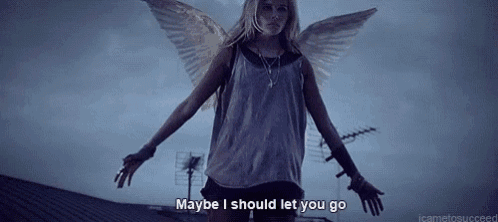 a woman with angel wings is standing on top of a roof .