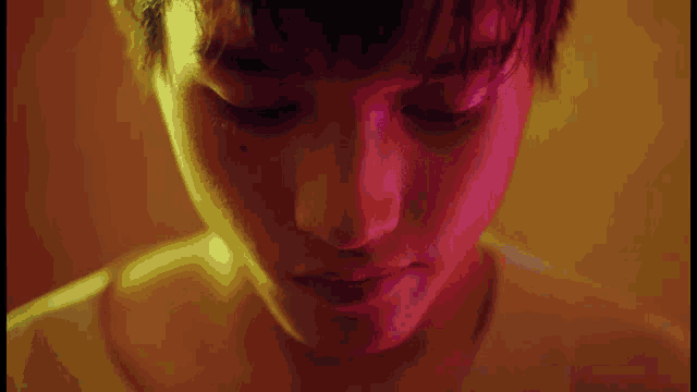 a close up of a person 's face with red and yellow lights behind him