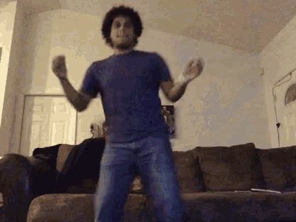 a man in a purple shirt and jeans is dancing in a living room