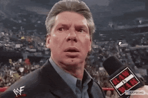 a man in a suit is talking into a microphone that says raw