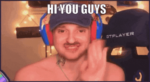 a shirtless man wearing headphones and a hat is waving at the camera .