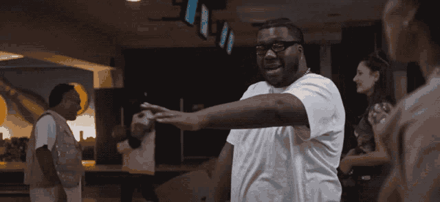 a man with glasses and a white shirt is pointing